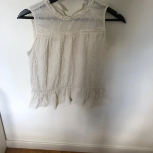 Vit ärmlös topp från Zara - Säljer en söt vit ärmlös topp från Zara i storlek XS. Toppen har fina spetsdetaljer och en volangkant längst ner. Perfekt för sommaren eller en fest. Toppen är i topp skick. Kom gärna med prisförslag!❤️