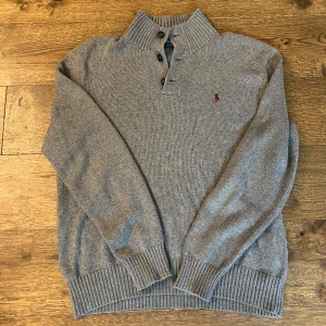Polo Ralph Lauren stickad tröja  - Säljer denna gråa stickade tröja från Ralph Lauren. Storleken är L men passar M. Tröjan är i bra skick och har inga defekter. Skriv om du har några frågor. Pris kan diskuteras vid snabb affär.