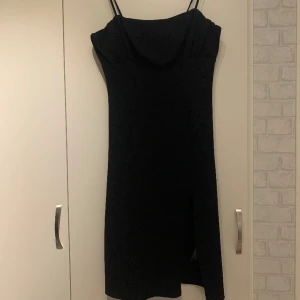Svart klänning med slits - Svart snygg sexig klänning som sitter tight på kroppen, smala Band och fin design vid bröstet samt en slits på vänster sida som ger det lilla extra. Har endast använts en gång. 
