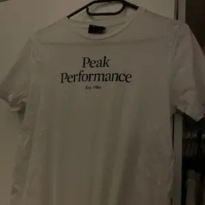 Peakferformance t-shirt i vit med marinblå text. Tveka inte höra av er vid ytterligare funderingar ☺️