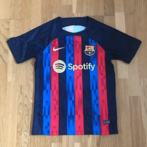 Barcelona Home 22-23 Jersey - Säljer min Barcelona tröja pga av att den inte kommer till någon användning. Använt max 2-3 gånger, inga konstigheter alls med produkten. Fraktar inom 24 timmar. Vill man ha fler bilder så är det bara att skriva så fixar jag det. Pris kan diskuteras.