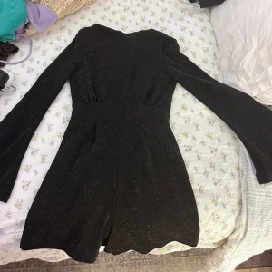 Glittrig fest klänning - Svart glittrig dress men öppen rygg och klockformade ärmar. Det är en jumpsuit ish.