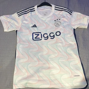 Ajax borta-tröja 23/24 - Fotbollströja Ajax 23/24. Använd 2 gånger. 10/10 skick. Kan sänka priset lite.  100 kr extra om ni vill ha shortsen till. Säg till om ni vill ha bild på shortsen 