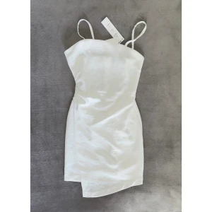vit klänning Zara XS/34 sommar vacay fest student stilren Helt NY! - Färg: vit.  Stel: XS.  Snygg klänning från Zara. Figursydd med drapering i ena sidan. Dold dragkedja och fina detaljer. Passar både vardags och fest! OBS - Helt NY & oanvänd, med lappar kvar!!