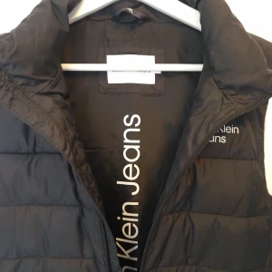 Calvin Klein-väst Som ny! - Svart väst från Calvin Klein, använd väldigt sparsamt. Som ny! Strl 16 - min son har haft den och han har XS i vanliga fall. Nypris 1000 kr.