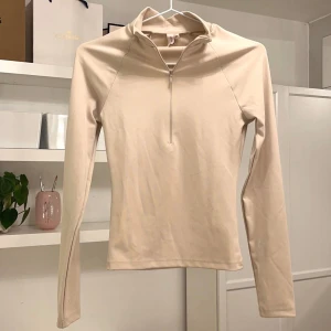 Half zip up träningströja - Träningströja från Nelly. Beige färgad. Den har en halv zip (dragkedja) i bysten och är hel täckande i ryggen. Den är aldrig använd och i nyskick, endast provad. Inga fickor. Storlek XS. 💗