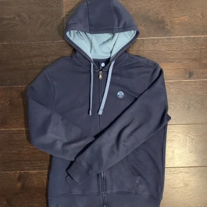 North sail fullzip tröja  - Tja säljer denna snygga fullzip tröja som är i färgen blå och är i storlek small och modellen på bilden är ca 180 lång.  Skick: 8/10 inga hål eller fläckar men den är använd, men är i ett väldigt gott skick fortfarande och ny pris är ca 1000kr 
