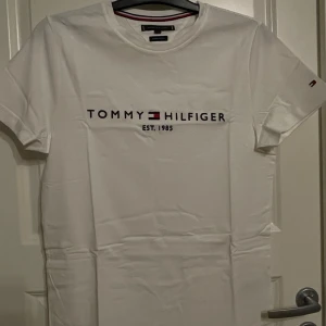 T-shirt Tommy Hilfiger - Vit T-shirt från Tommy Hilfiger med tryck över bröstet. Fint skick.