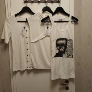 Tre vita toppar - Två oanvända toppar med taggar kvar från märket visual clothing project som säljs på MQ Ett oanvänt linne med tryck från den svenska designern Kan Dee. Allt i storlek Small
