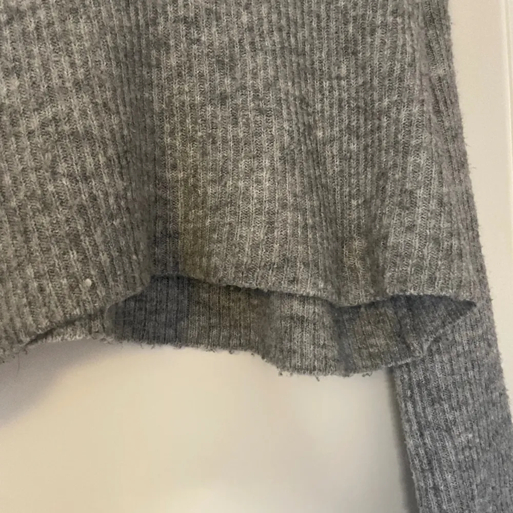 Grå stickad tröja med halv-polokrage, är lite kortare i modellen och har vida ärmar. Den är en del nopprig därav priset!. Stickat.