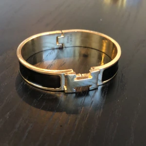 Armband klassiskt - Svart med guld I använt skick 