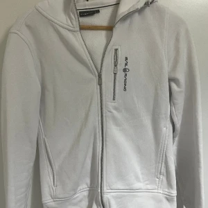 Sail racing ziphoodie - Vit sail racing hoodie i storlek small. Använd ganska många gånger men är i väldigt bra skick. Säljes pga jag inte använder den längre. Köpt för 1300 säljes för 300. Pris kan diskuteras 