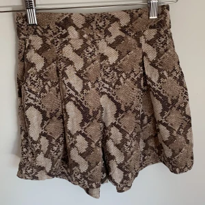 Ormskinns mönster shorts hm stl 34 xs - Coola svala shorts från Hm med ormskinns mönster. 2 fickor och resår i bakre linning. Stl 34, xs.