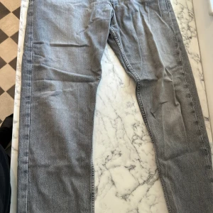 Gråa jeans från Jack & Jones  - Ett par gråa Jack & Jones jeans i storleken 32/30. Jeansen har använts ett par gånger och är fortfarande i gott skick. Jeansen är av mjukt material, lätt att röra sig med och passar bra med alla olika kläder. Jeansen har nu blivit för små på mig. 