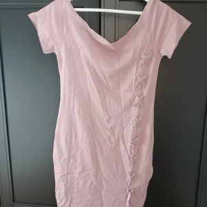 Klänning  - Fin rosa klänning. Skönt slätt material som är formande och lite elastiskt. Lätt att ta av o på. Snören på sidan som dekoration. Sällan använd och säljer den därför nu. Finns inga fläckar eller märken på den. Pris kan diskuteras 