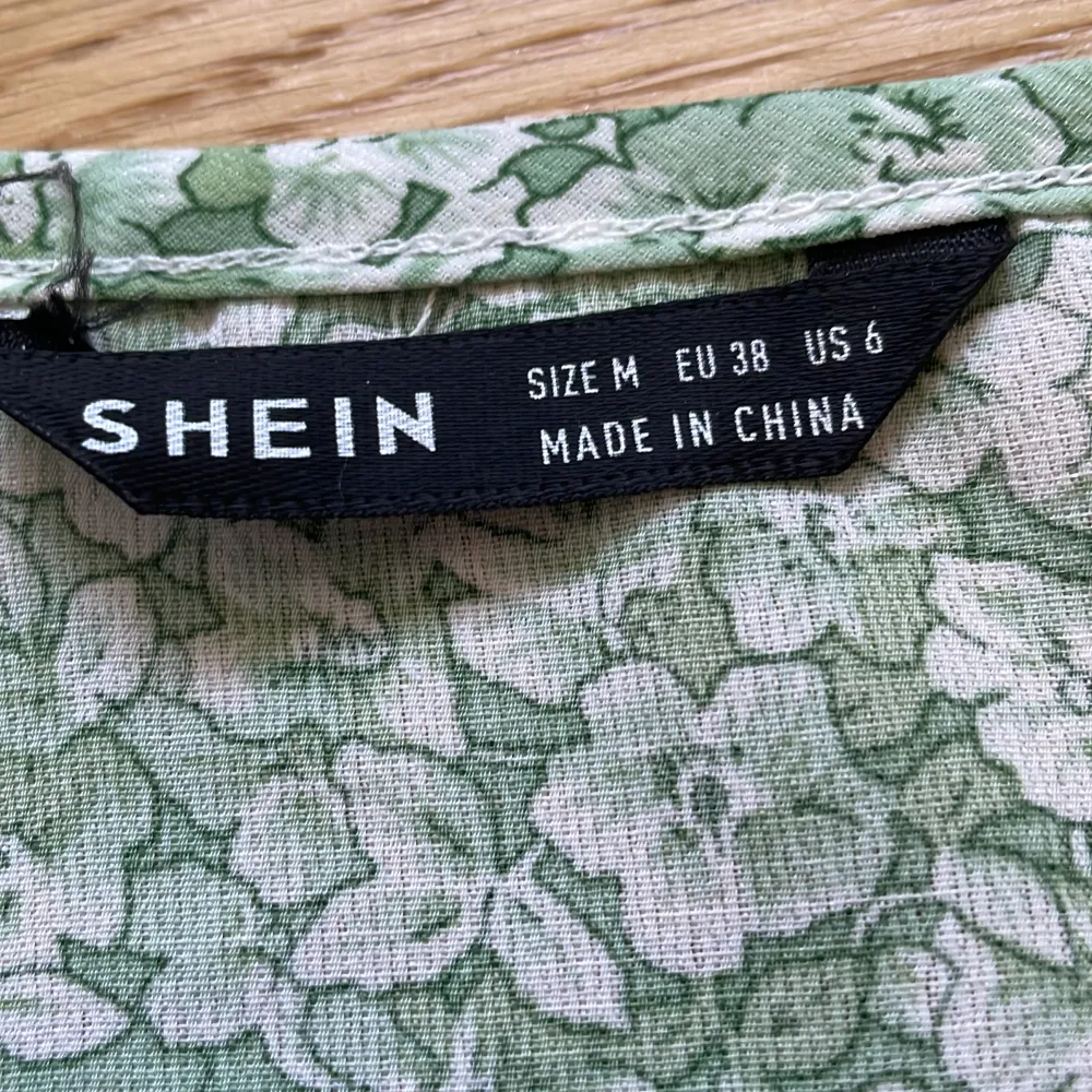 En grönblommig klänning med v-ringning från Shein i storlek M. Jag säljer eftersom att jag inte passar i den.. Klänningar.
