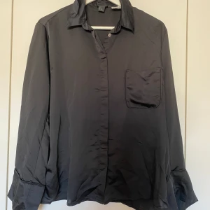 Svart skjorta - Svart skjorta i glansigt material, storlek S. Ursprungligen ifrån ett pyjamas-set från H&M