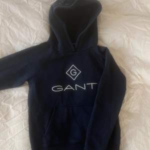 Säljer denna hoodie från Gant i barnstorleken 146/152 i en marinblå färg. Den har använts ett fåtal gånger och är fortfarande i superbra skick!🫶🏽