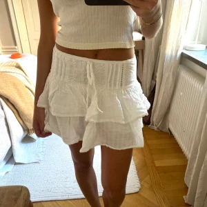 Vit lågmidjad volangkjol  - Säljer min fina volangkjol från Pull&Bear i storlek XS. Sitter perfekt lågmidjat och har så fint broderi som ger extra detalj! Använd mycket men ser som ny ut☀️☀️ (dragkedjan är lite trög i mitten, annars i jättefint skick) 🍓
