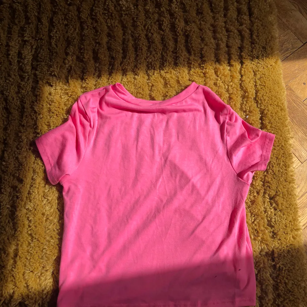 En rosa kortare T-shirt med mörkrosa bikini format tryck. T-shirts.