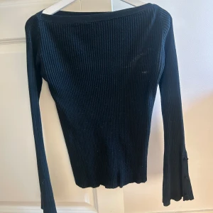 Stickad tröja - Stickad tröja med utsvänga armar. Knappar längst ut på ärmarna