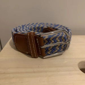 Flätat Grich Bälte - Använt fåtal gånger, riktigt trendigt med beige och blå färg som passar extremt bra med ljusa jeans.
