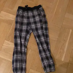 Ett par rutiga pyjamasbyxor från KappAhl i storlek 146/152 i färgen svart och grå