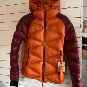 Skhoop Dunjacka Klara Burnt Orange - Superfin! Helt ny dunjacka Klara Down Jacket från Shkoop, en lätt jacka som funkar både i och utanför skidbacken. Smuts- och vattenavvisande yttermaterial med dekorsömmar i form av ett rombmönster. Fyllning av RDS-cerifierad 90/10 dun/fjäder. 