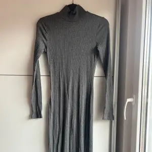 En ganska lång grå ”stickad”klänning som går upp till halsen. Knappt använd och är i bra skick. Storlek S