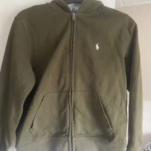Polo ralph lauren zip hoodie - En olivgrön zip hoodie från Ralph lauren i bra skick👌🏼barnstolek M, passar väl någon som är runt 10-14 år!! 
