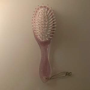 En rosa glittrig hårborste, står även ett D på den, men kan vara användbar ändån❤️liten silver kedja längst ner på borsten, Som gör att du kan hänga det på typ en väska eller något😂