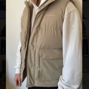 Les Deux Väst - Les Deux Maddox Puffer Vest i färgen ”Dark sand”! Säljer åt min pojkvän då den inte riktigt kommit till användning här hemma. Snygg bäst med magnet fickor! Nypris 2499kr mitt pris 1999kr!  