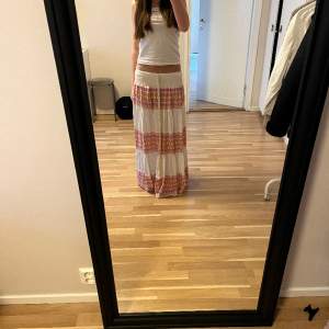 En vit lång kjol med rosa och orange mönster på💕   (Ny pris 850) priset kan diskuteras ❤️