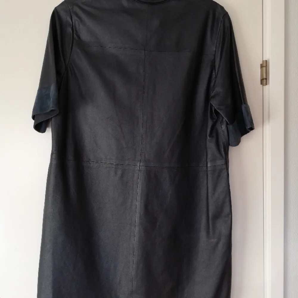 En svartblå lång kortärmad skinnskjorta från HM som kan funka som kort klänning. I mycket bra skick. I en mörkt blå färg som nästan kan uppfattas som svart. . Skjortor.