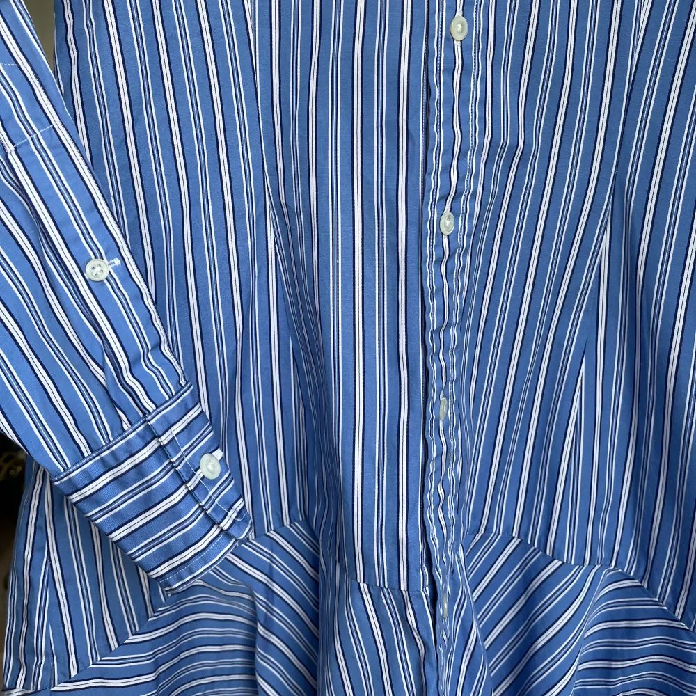 Polo Ralph Lauren figursydd Skjortklänning vitblå-randig. Perfekt skick, som oanvänd. ”Kjolen” går asymmetriskt, längre i bak och kortare i fram.. Klänningar.