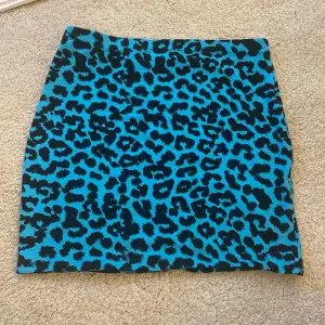 Egen sydd blå kjol med leopard mönster. Sytt av den likadant som en butiks köpt kjol i storlek M. Kjolen har resårband rund midjan så den ska ha bättre passform. Midja 30cm rakt över. Längd 40cm. (Stretchigt tyg)