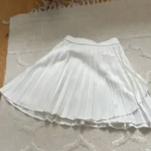 Det är en kort vit kjol med en fin volang på sidan.
