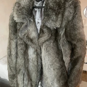 Pälsjacka - Fin grå pälsjacka i bra skick! Skiftar i vit och grått. Lite längre modell, går nedanför rumpan. 