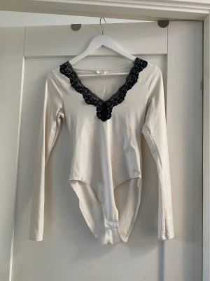 Spetsbody - Frakt: 66kr, Betalning sker via swich Vit body som är lite mer krämvit i färgen med svart spets🫶