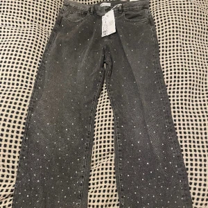 Gråa jeans - Gråa jeans med små diamanter på, köpt från gina tricot. De är ganska vida i benen. Helt nya med prislapp kvar. Passade tyvärr inte mig men hann inte lämna tillbaka i tid.
