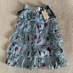 By Malina rutig blommig volangkjol - Otroligt vacker kjol från ByMalina. Storlek XS men passar även S. Finns en dold dragkedja på sidan. Ny med tags kvar, utan anmärkningar.