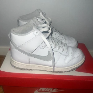 Nike Dunk höga  - Nike Dunk High i vit färg med gråa detaljer. Köpta från Zalando. Originalboxen ingår samt extra snören i grå färg. Storlek 37.5. Som ni ser är de nästan helt oanvända.