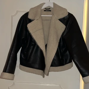 Skinn jacka med teddy detaljer - Svart skinn jacka med teddy detaljer på ärmarnas utsida och jackans insida. Använd 2-3 gånger, jackan är i nyskick.