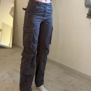 Cargobyxor - Grå bruna cargobyxor från asos, kommer inte till användning så i fint skick, meldelhög midja. Vid fler frågor eller bilder är de bara att skicka i chatten. Köparen står för frakten💕
