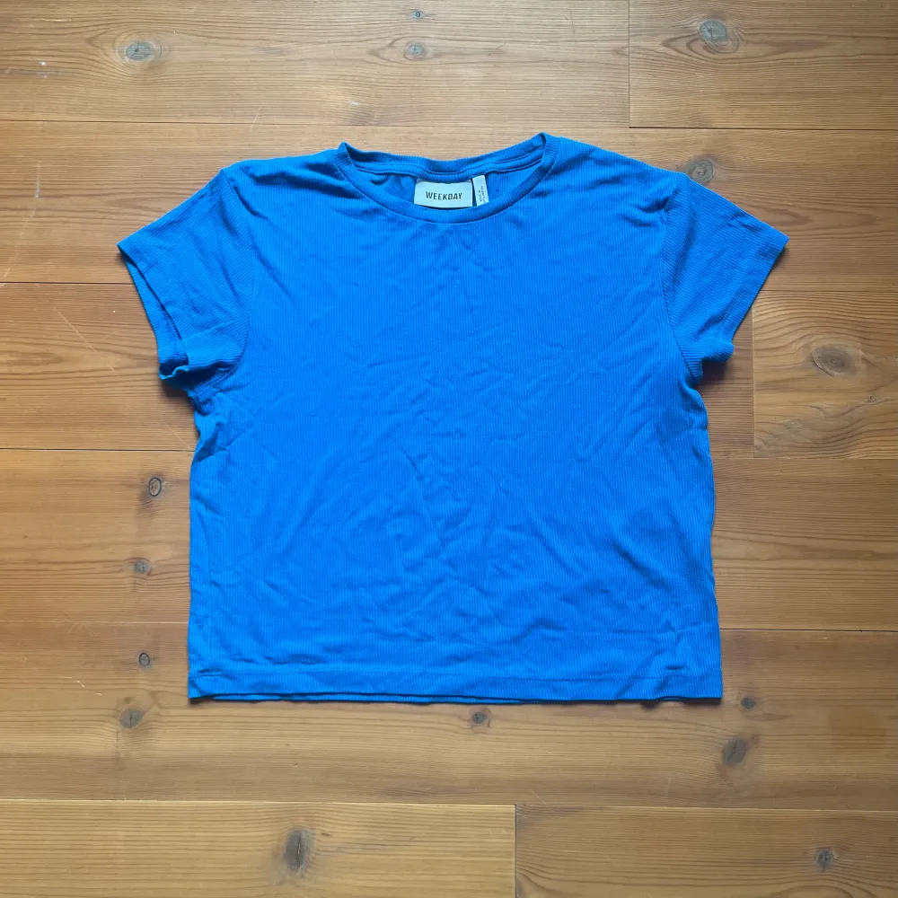 Kort, tajt t-shirt i en klar blå färg. Fint skick och i ribbat material. . Toppar.
