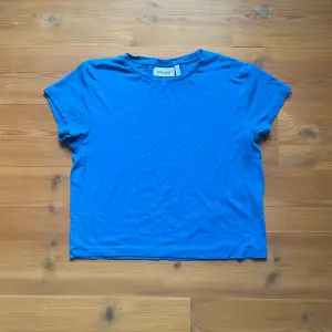 Kort, tajt t-shirt i en klar blå färg. Fint skick och i ribbat material. 