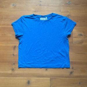 kort topp  - Kort, tajt t-shirt i en klar blå färg. Fint skick och i ribbat material. 