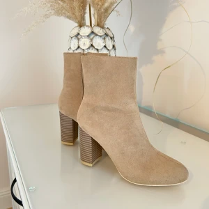 Beiga klackskor - Klackskor från Nelly. Storlek 38. Använd ett fåtal gångar (syns endast under skorna). Aningen tajta i vaderna. Passar små-mellanstora vader. Kommer ej gå att stänga om du har stora vader. 