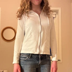 Luvtröja med dragkedja  - Väldigt gullig vit luvtröja med dragkedja som tyvärr aldrig kommer till användning. I bra skick och jätteskönt material med så fin passform. Perfekt som tunnare jacka till sommaren. 