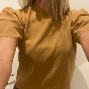 Topp - Senapsgul t-shirt med något längre och lite puffiga armar. Nyskick!